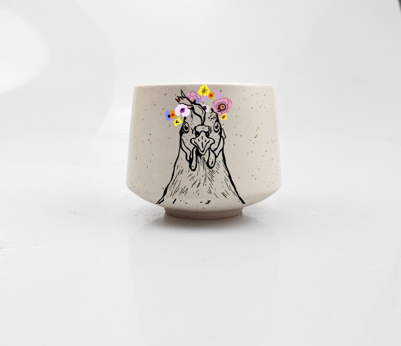 Artsy Ems Designs white ceramic Artisan Chicken Cup features a black line drawing of a chicken with pastel flowers, making it a charming and whimsical addition to any home decor.